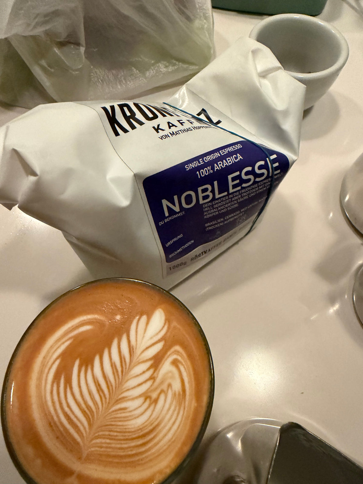 Noblesse: 1-kg-Beutel neben einem Cappuccino mit Latte Art