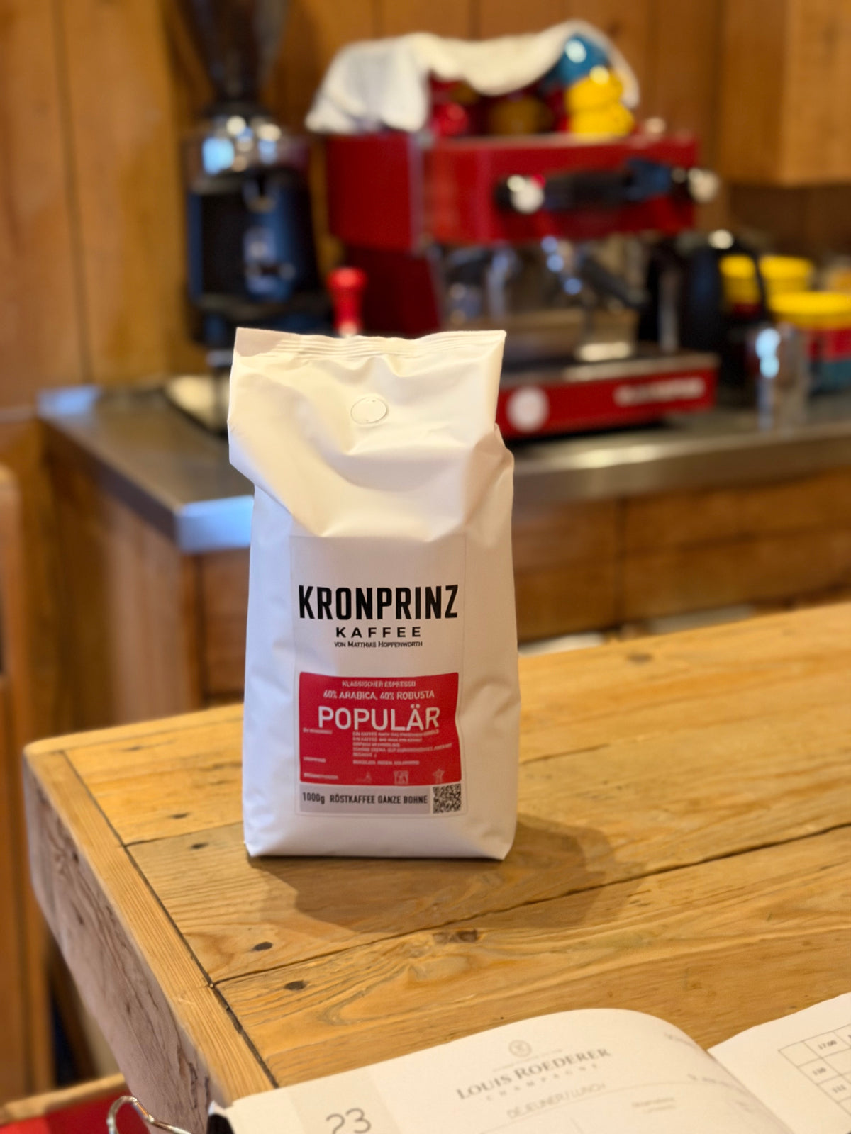 Populär, 1-kg-Beutel vor einer roten Siebträgermaschine